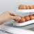 Refrigerator Egg Rolling Organiser for Storage with eggs being placed in a stacked holder in the fridge.