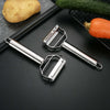 Stainless Steel Handheld Vegetable & Fruit Peeler next to a potato, cucumber, and carrot on a cutting board.