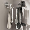 Suction cup wall hooks for storage holding kitchen utensils and a towel on a smooth wall surface.