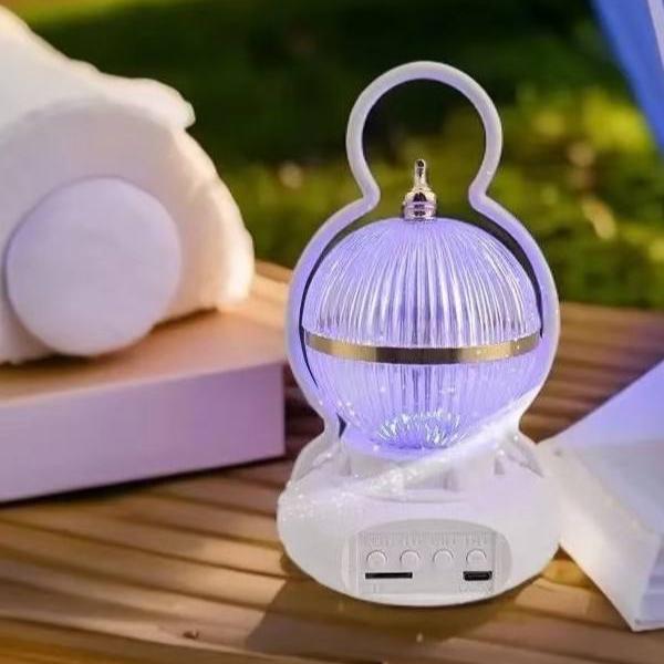 Rechargeable LED Camping Lamp with Bluetooth Speaker on a table outdoors, providing light and music.