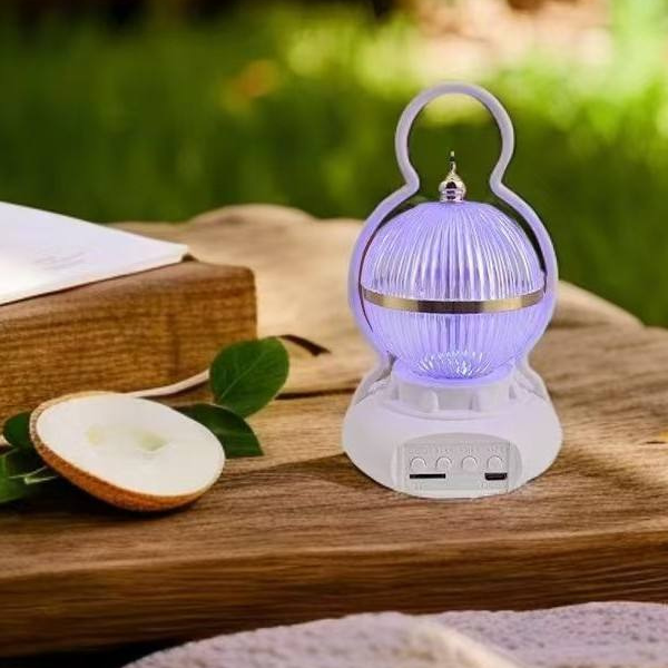 Rechargeable LED Camping Lamp with Bluetooth Speaker on a wooden table with an apple slice.