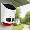 Solar Garden Light Motion Sensor Alarm mounted on a house, featuring a solar panel and a red flashing light for security.