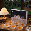 12 Piece Embossed Glass Coffee Cup and Saucer Set displayed on a wooden table with warm beverages and elegant decor.