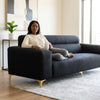 Modern Black 3-Seater Sofa with Gold Metal Legs in a stylish living room setting with a woman relaxing.