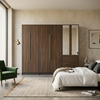 4 Door Wardrobe with Mirror and Drawers in modern bedroom setting with green chair and patterned rug.