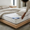 1.5M Comfort Sleep Mattress Person adjusting the 1.8M Comfort Sleep Mattress on a stylish wooden bed frame in a modern bedroom setting.