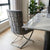 Grey Upholstered Dining Chair with Silver Frame placed beside a marble dining table in a modern interior.