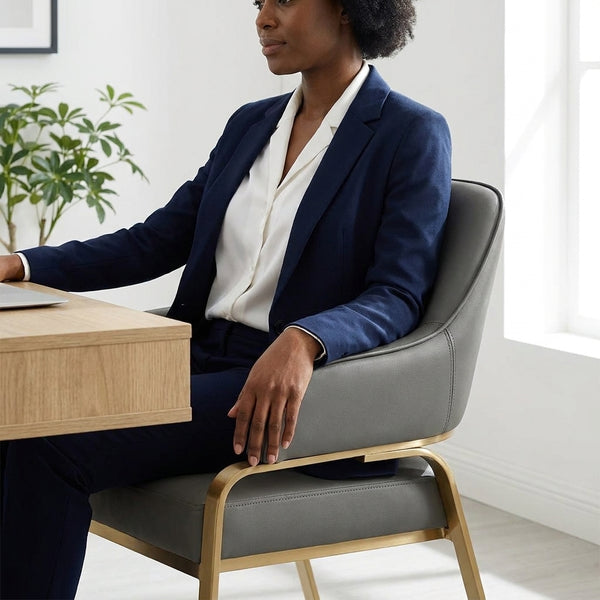 Woman seated in Sunpan Malachi Dining Armchair, stylishly dressed at a modern desk.