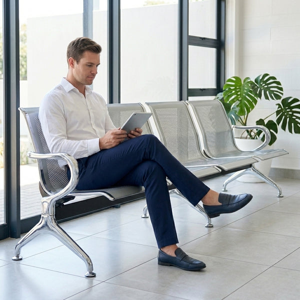 Man sitting on a Heavy-Duty Stainless Steel Public Seating Bench, using a tablet in a modern waiting area.