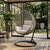 Hanging Egg Chair with Stand and Cushions in a beautifully designed indoor space with greenery.