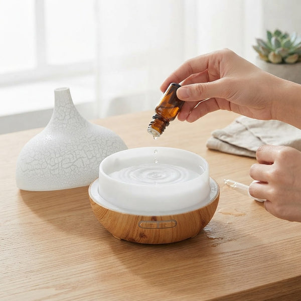 Hand adding essential oil to Ultrasonic Aroma Air Humidifier & Essential Oil Diffuser on a wooden table.