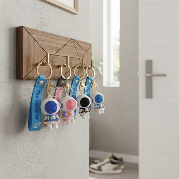 4 3D Silicone Astronaut Keychains hanging on a wooden key holder with a modern design.