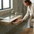 Woman opening a drawer of a Tempered Glass Console Table in a modern living space.