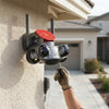 4-Lens PTZ Wi-Fi Security Camera Unit mounted on a wall with a hand adjusting it.
