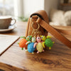 Colorful 3D Rubber Sea Turtle Keychain attached to a stylish brown handbag on a wooden table.