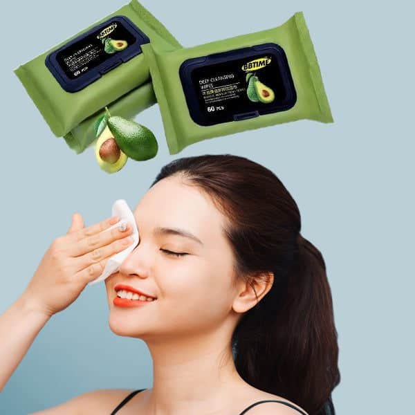 Avocado Deep Cleansing Wipes being used by a woman to refresh her skin, with wipes and an avocado in the background.