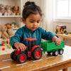 Child playing with a Plastic Farm Tractor Toy with Detachable Green Trailer on a table.
