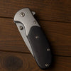 Engraved Wilderness Tactical Folding Knife on a wooden surface, showcasing its sleek design and durable materials.