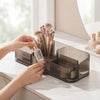 Multi-Compartment Cosmetic Desktop Storage Box with makeup brushes and skincare bottles on a dressing table.