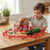 Child playing with the Happy Farm House Play Set, featuring animals and a toy barn on a table.
