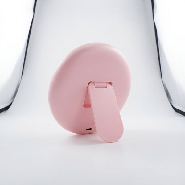 Back view of the Round Portable Makeup Mirror showcasing its pink color and integrated stand design.