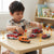 Child playing with Die-Cast Model Alloy Cars Emergency Rescue Vehicle Gift Set on a table among traffic signs.