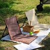 Two Ultra-Lightweight Folding Portable Camping Chairs in brown and beige on a picnic blanket with a basket and snacks.