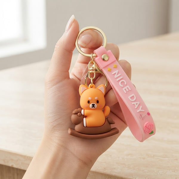 Cartoon Animal Keychain featuring a cute orange bear on a rocking chair with a pink strap that says 'NICE DAY'.
