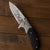 Engraved Wilderness Tactical Folding Knife featuring a detailed blade design and sturdy handle on a wooden surface.