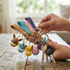 Color Monster Creature Sphere Keychain with Wrist Strap in hand with multiple colorful character charms and keys.