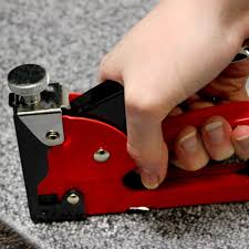User demonstrating the GS Manual Nail Staple Gun while fastening materials on carpet.