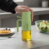 Clear Glass Spray Atomization Oil Bottle with green spray top, used for evenly oiling food in the kitchen.
