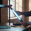 Person holding a Rechargeable Magnetic LED Work Light Bar while working on a project in a dimly lit room.