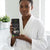 Woman holding Anti Hair Loss Shampoo Natural Plant Extract in a bathroom, promoting healthy hair regrowth.