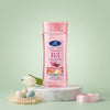 Vitamin B3 Vitamin E Body Oil Gel in a pink bottle on a marble surface with flowers and decorative eggs.