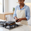 A person using a Double-Sided Aluminum Toast Maker on a gas stove in a modern kitchen.