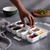 Hand reaching for spices in the Jumbo Spice & Pantry Organizer with various compartments.