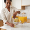 A woman serving juice from an Acrylic Beverage Dispenser 5.5L in a stylish kitchen.