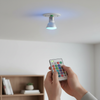 Smart RGB LED Color-Changing Bulb with Remote being controlled by a person using a remote in a modern setting.