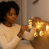 Woman arranging Ramadan Eid String Lights Decoration with moons and stars on her bedroom wall.