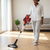 A person using a 2000W Handheld & Stick Cordless Vacuum Cleaner on hardwood floors in a bright living room.