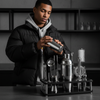 18 Piece Cocktail Shaker & Bar Tool Set with Wooden Stand showcased with a young man preparing a drink.