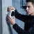 Man installing a Security Camera 1080P HD Wireless WiFi Rechargeable Battery on a concrete wall.