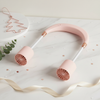 Portable Hanging Neck Fan in soft pink color on marble surface with decorative elements.