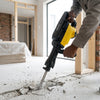 Person using a 1500W Heavy-Duty Demolition Jack Hammer & Concrete Breaker to break concrete floor.