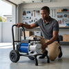 Electric High Pressure Airless Paint Sprayer setup in a garage by a man inspecting the machine.