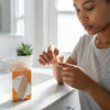 A person applying a Breathable Waterproof Adhesive Bandage while standing by a bathroom sink.