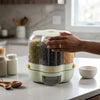 6-Grid Rotating Rice and Grain Dispenser with hand reaching for grains on a countertop.
