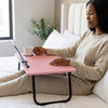 Woman using Ergonomic Folding Computer Desk in bed with a cup of coffee, showcasing height and angle adjustments.