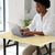A woman using a laptop on a Single Computer Training Desk in a bright, organized workspace.